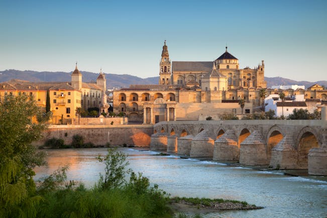 Pink tinged sunlight on the Mezquita cathedral by the river in Cordoba