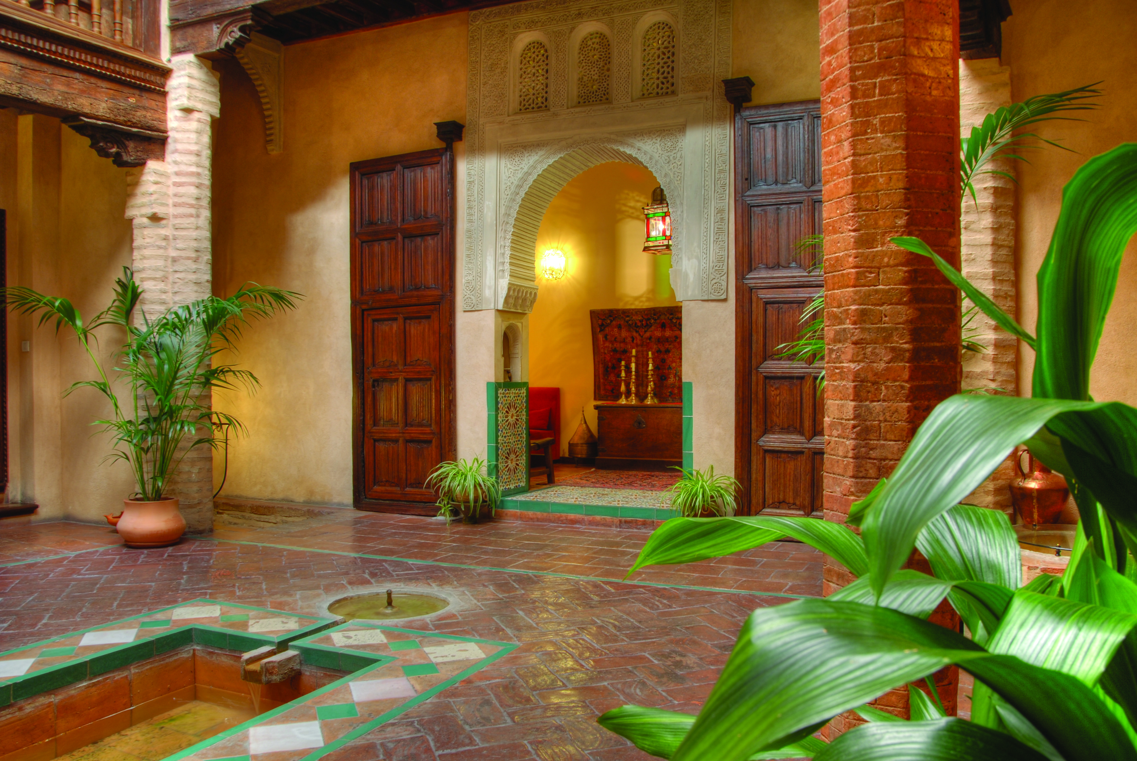Casa Morisca patio with brick pillars, an archway and wooden doors 