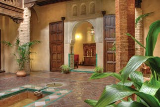 Casa Morisca patio with brick pillars, an archway and wooden doors 