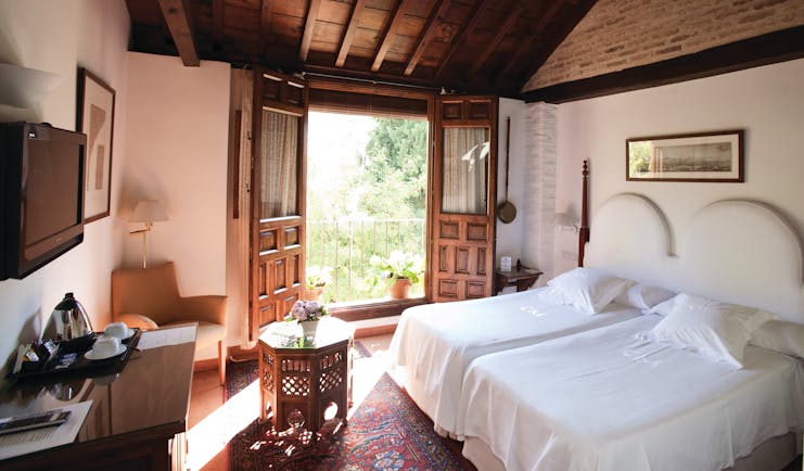 Standard room at the Casa Morisca with a double bed, television and double wooden doors leading onto a balcony