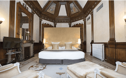 Palacio de los Patos Granada junior suite bed armchairs modern décor ornate ceiling 