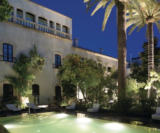Palacio del Bailio Andalucia pool side at night lit up pool sun loungers trees