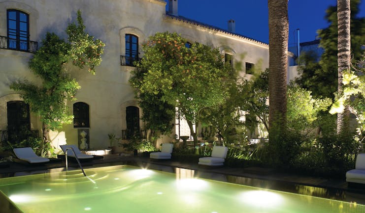 Palacio del Bailio Andalucia pool side at night lit up pool sun loungers trees