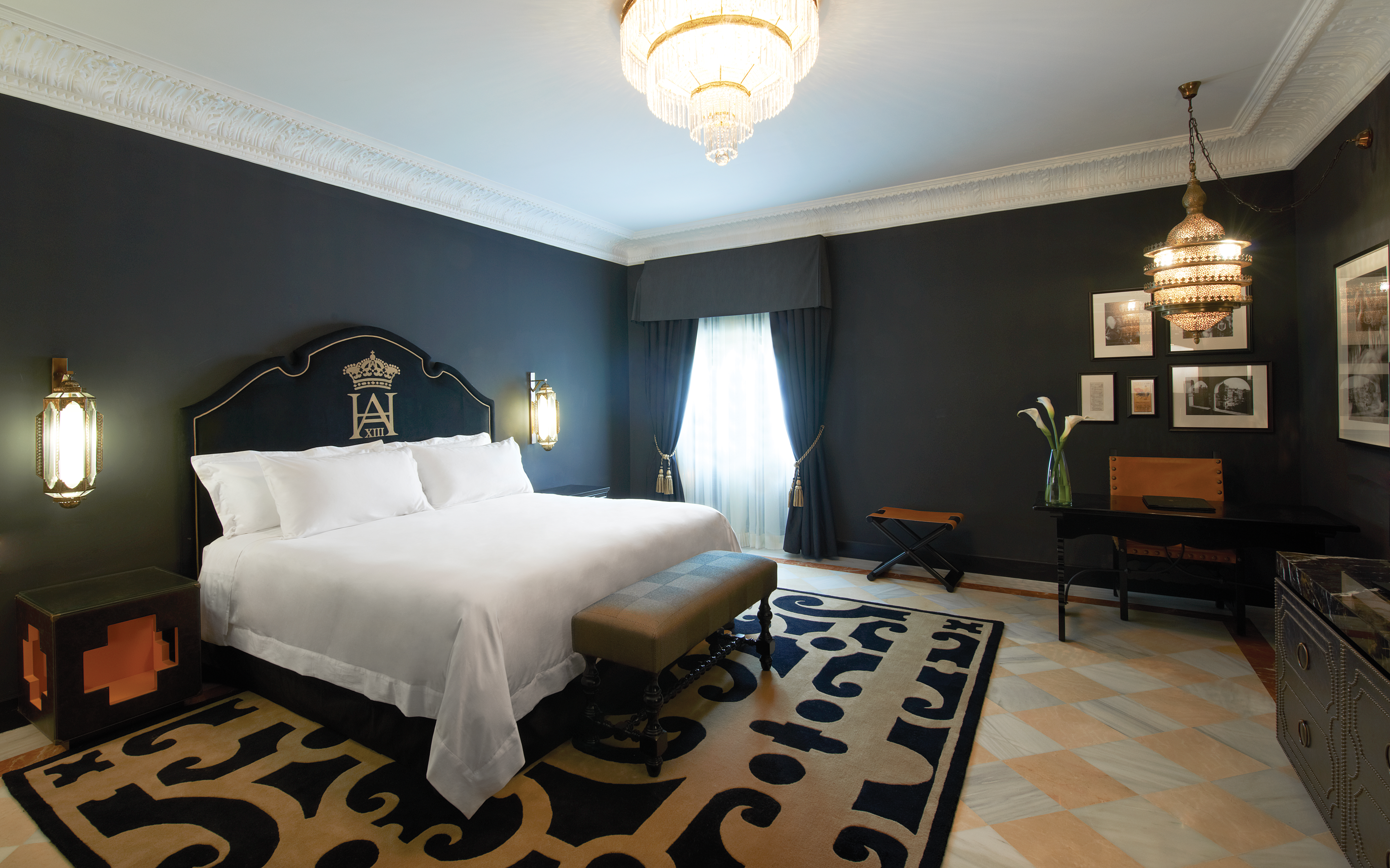 Suite with large double bed, chandelier, television and chairs