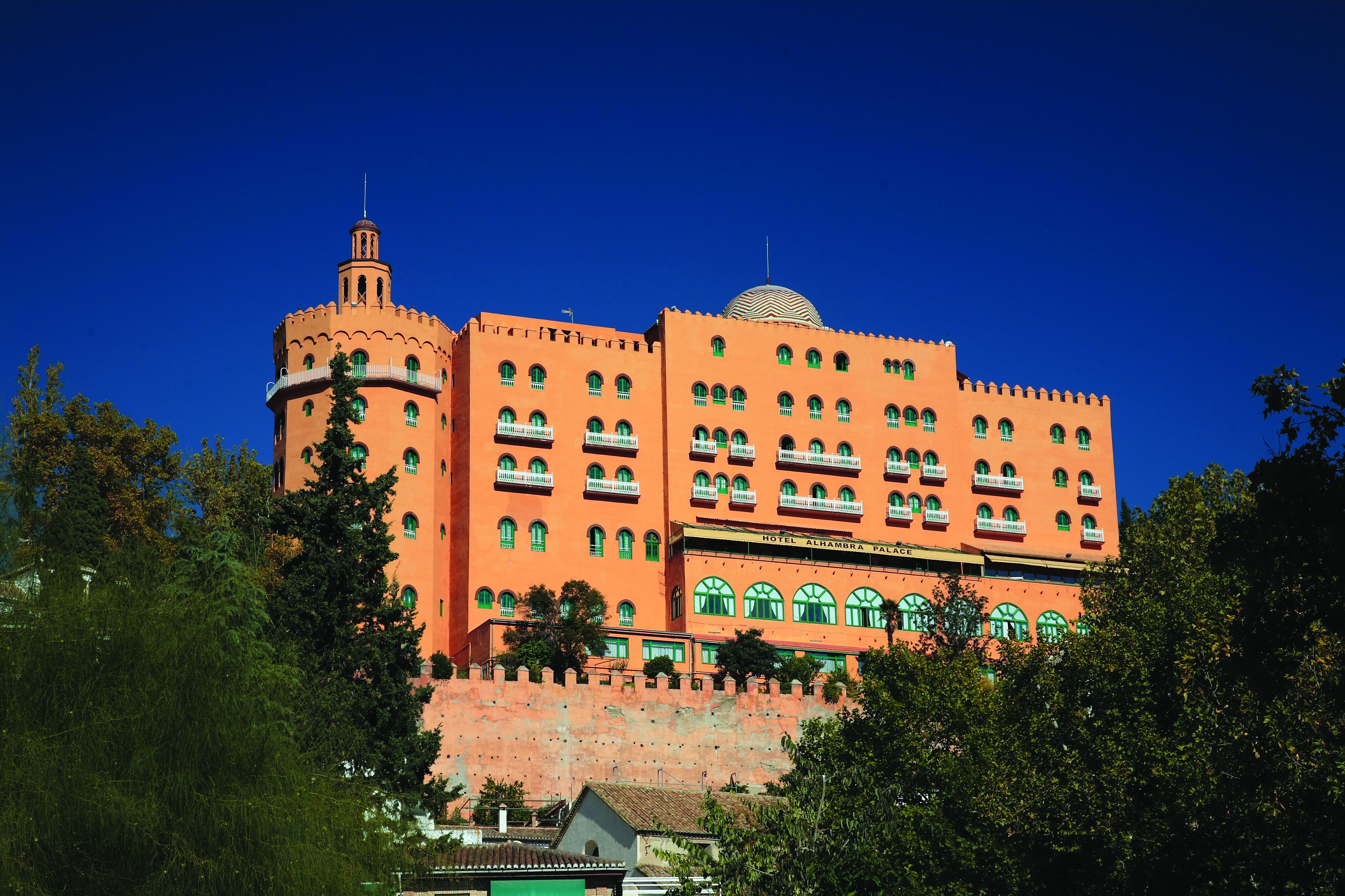 Exterior of the Hotel Alhambra Palace, a large orange building with small green windows