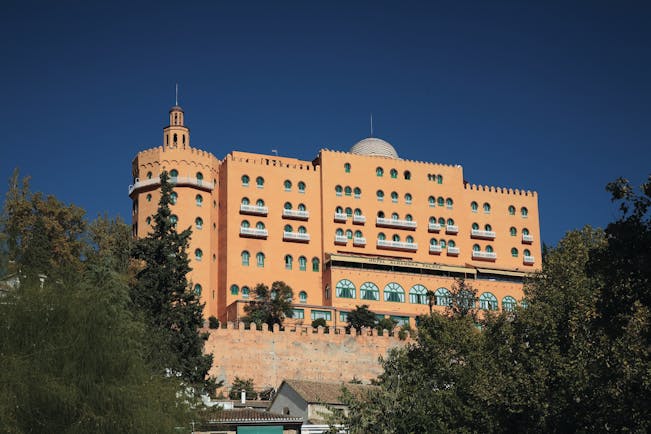 Exterior of the Hotel Alhambra Palace, a large orange building with small green windows
