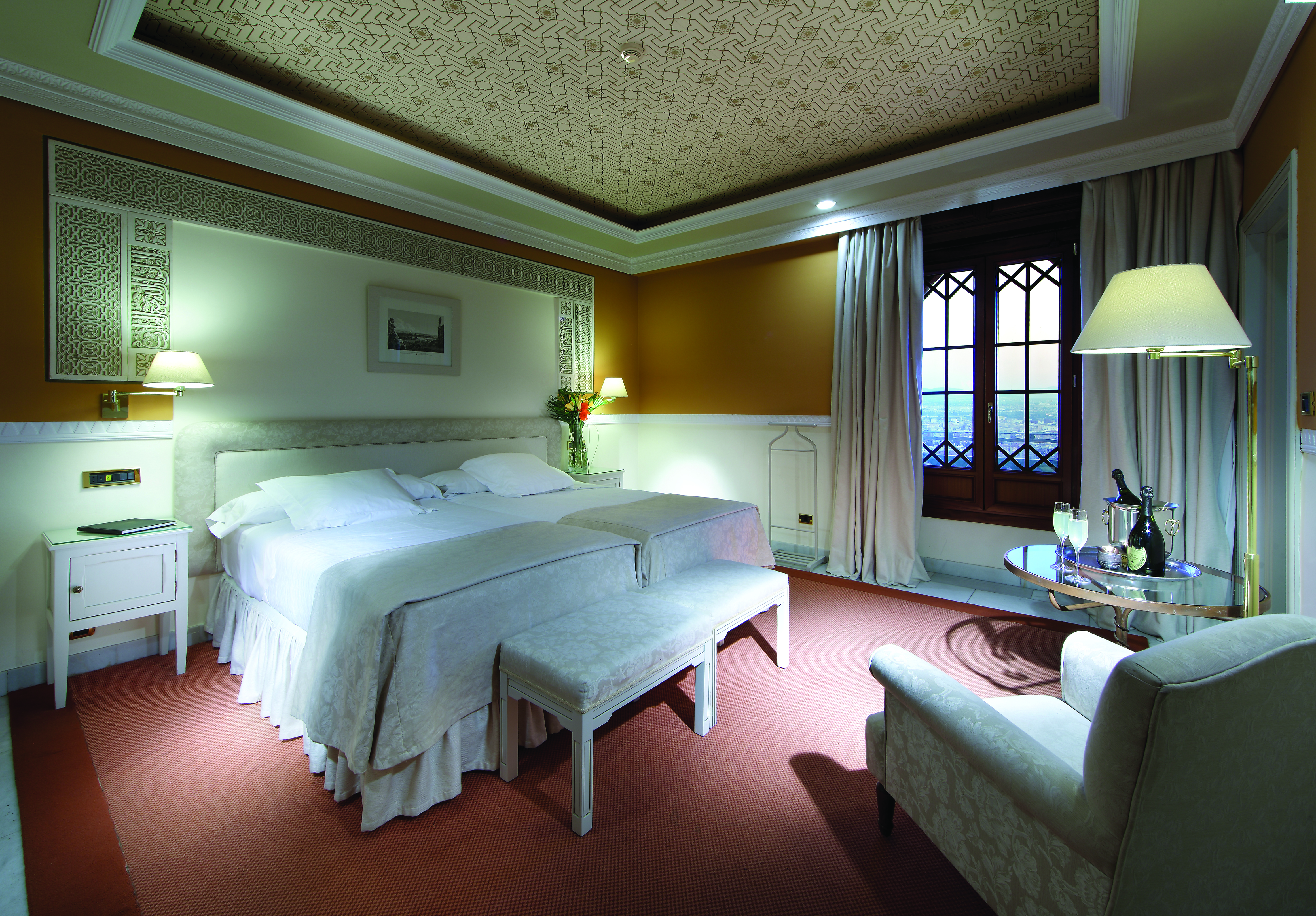 Twin room with city views, red and yellow colour scheme, large white bed with armchair