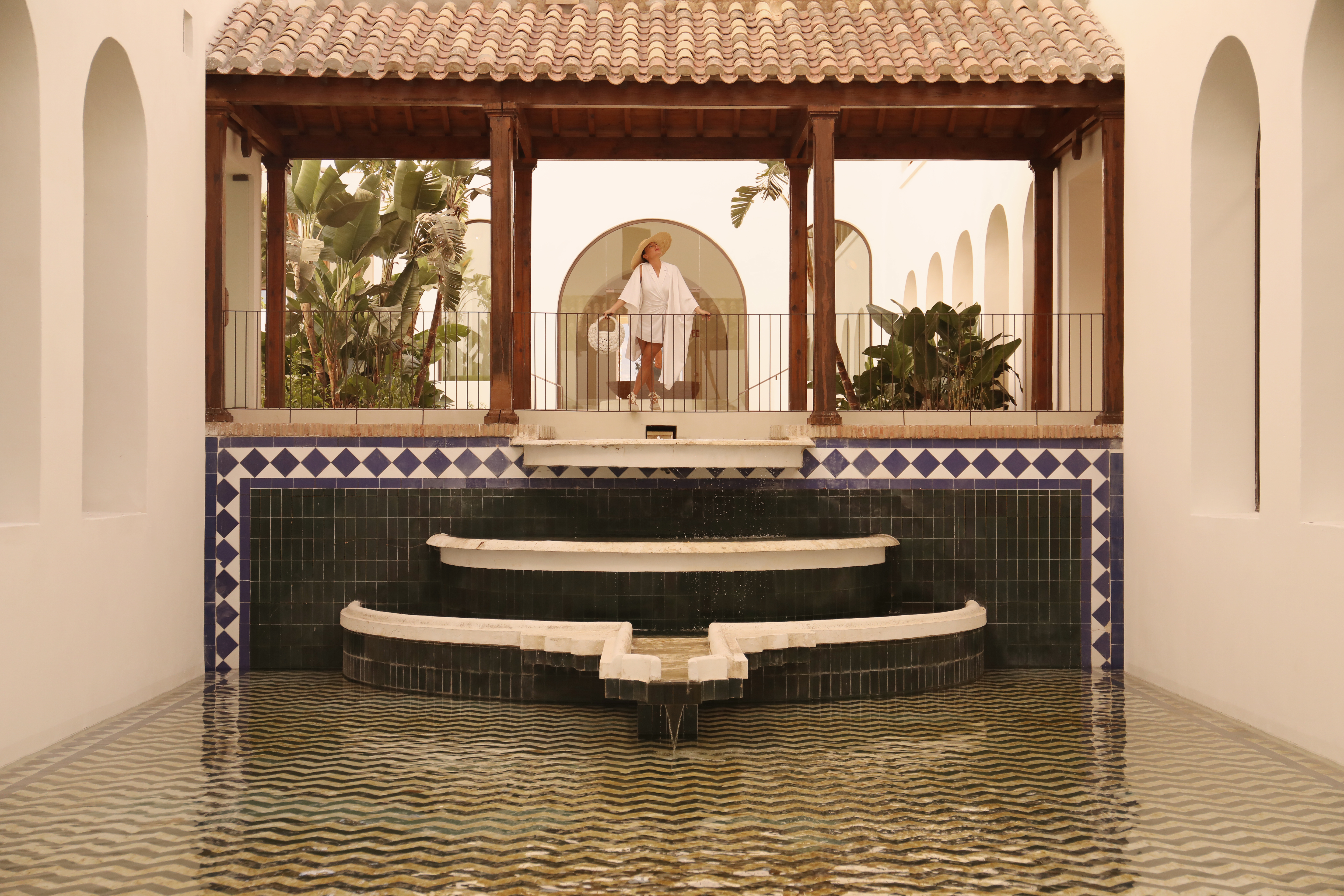 La Zambra Resort fountain with blue tiles and three tiers, with woman standing on sheltered walkway