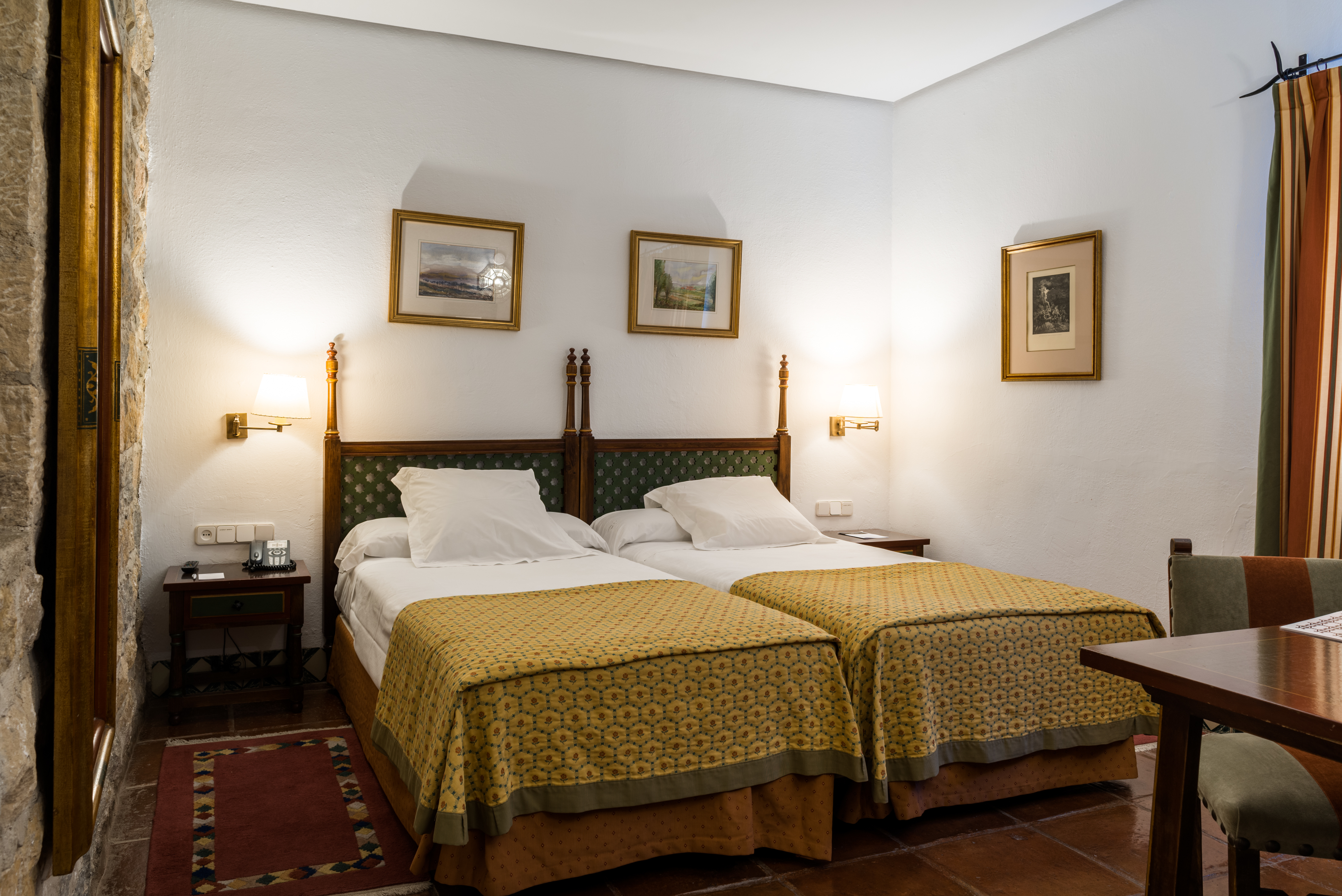 Twin bedded room with white alls and yellow bedspreads at the Parador de Jaen