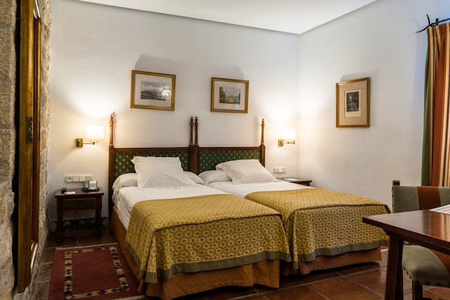 Twin bedded room with white alls and yellow bedspreads at the Parador de Jaen