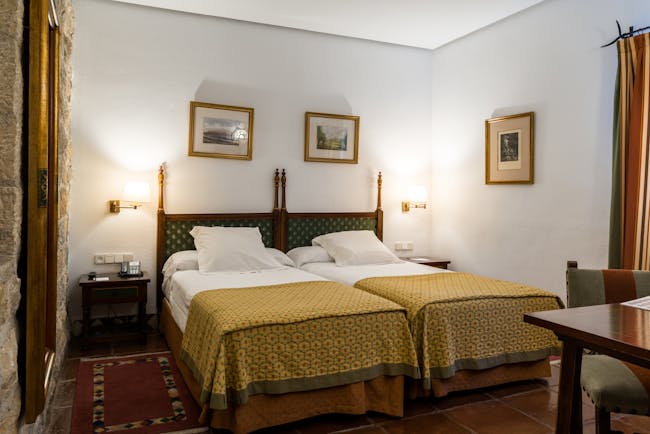 Twin bedded room with white alls and yellow bedspreads at the Parador de Jaen