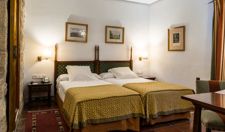 Twin bedded room with white alls and yellow bedspreads at the Parador de Jaen
