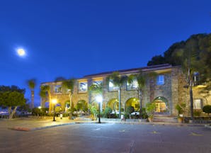 Parador de Malaga Gibralfaro exterior at night, traditional architecture, moon in night sky, pine trees