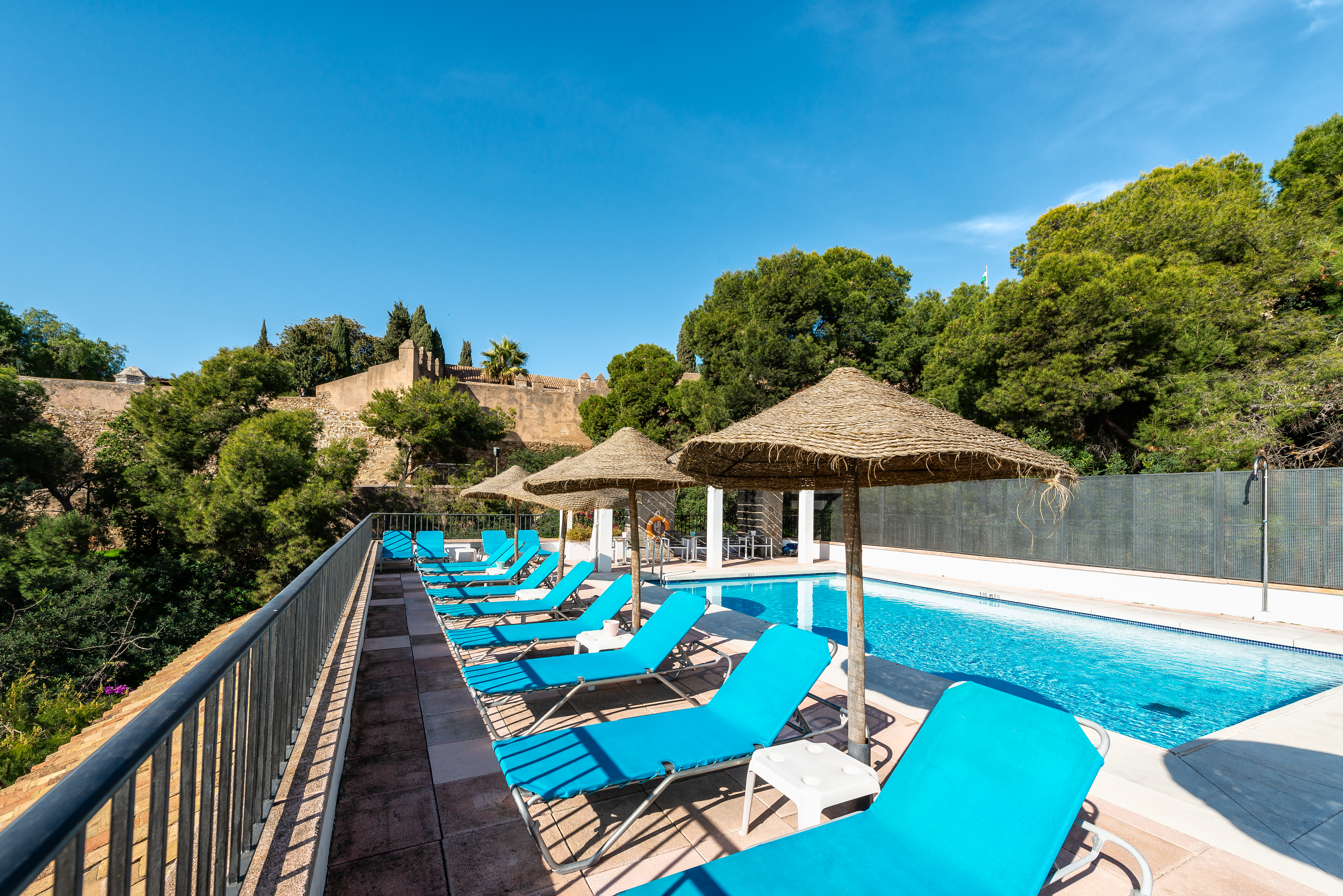 Parador de Malaga Gibralfaro pool, sun loungers, pine trees in background