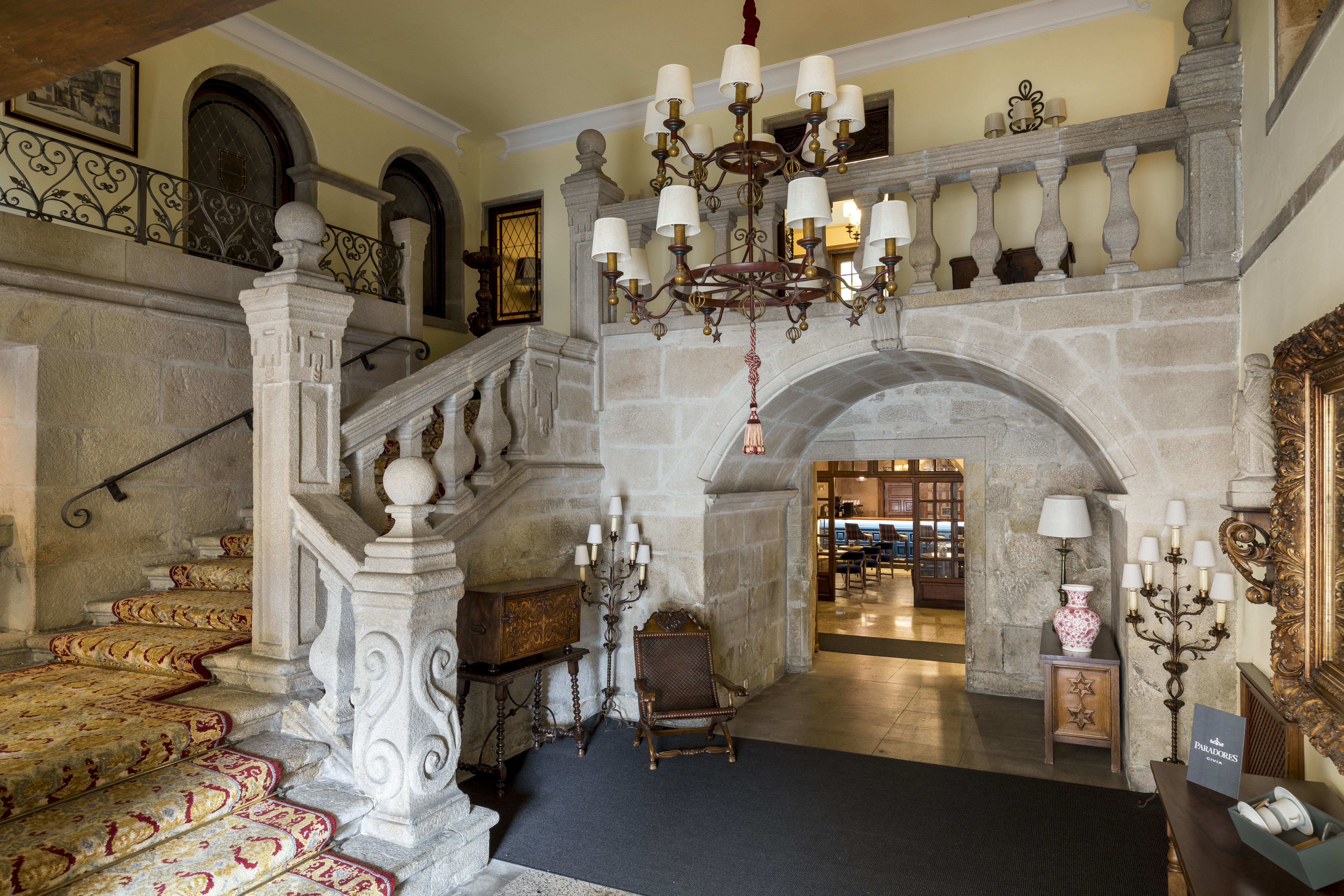 Parador de Pontevedra lobby, ornate stone staircase, carvings, carpet, chandelier, traditional decor