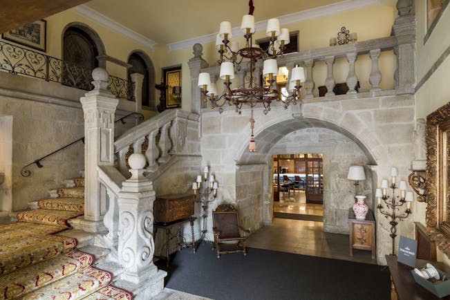 Parador de Pontevedra lobby, ornate stone staircase, carvings, carpet, chandelier, traditional decor