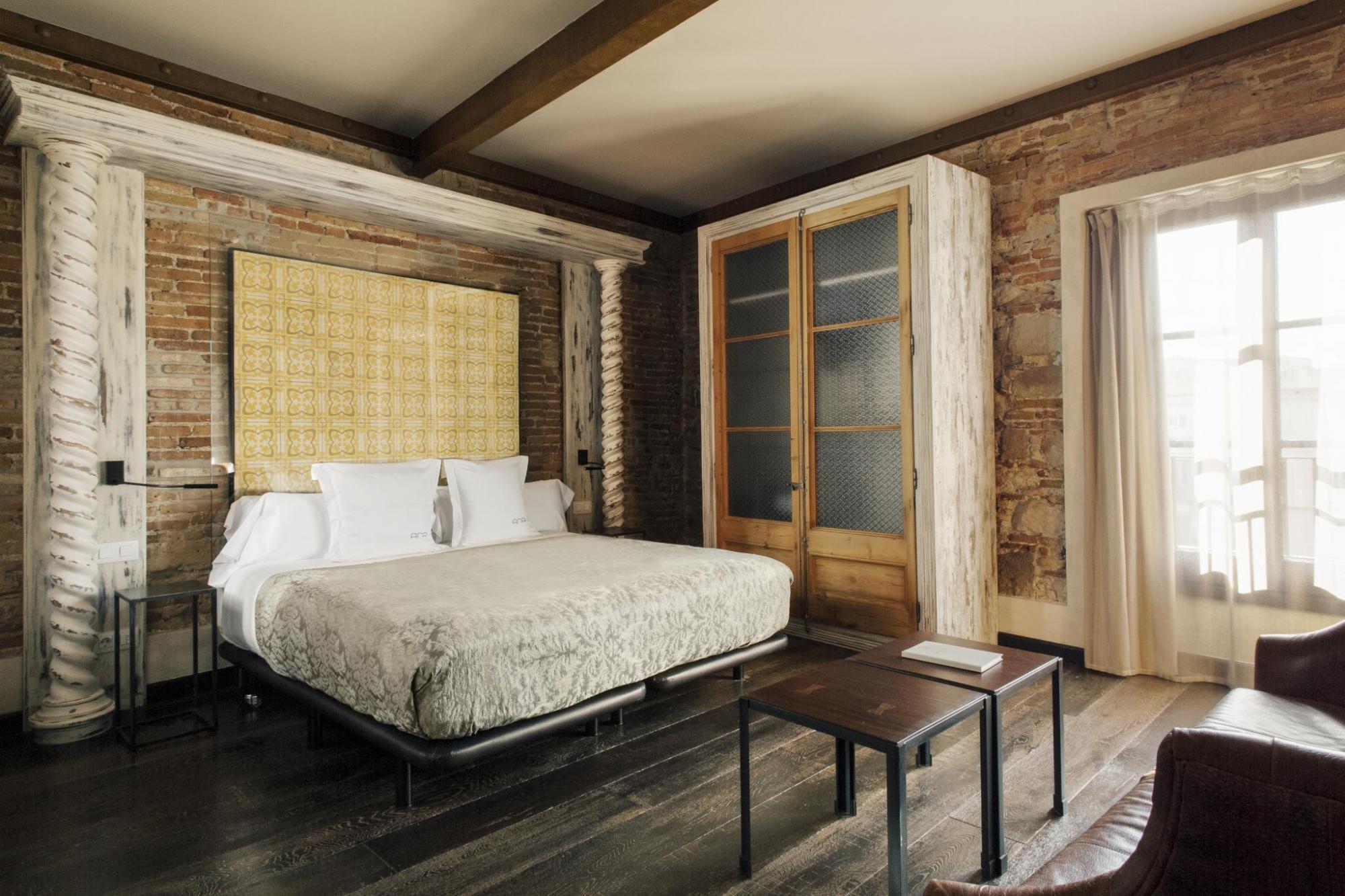 Hotel Arai Deluxe Room with stone walls, wooden furnishings and features, neutral colour palette with touches of lemon yellow, and french doors