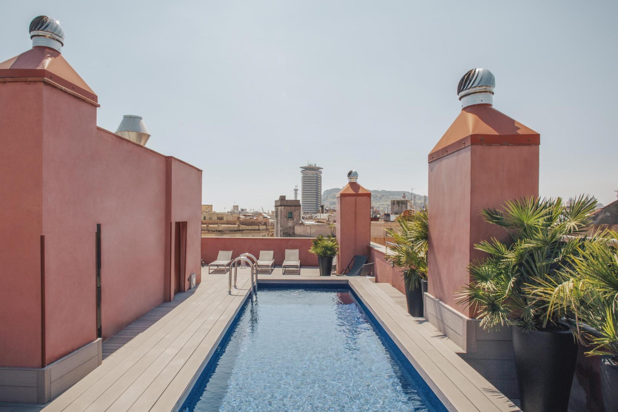 Hotel Arai rooftop pool, designed for lengths, with pink walls, plants, and views of the city