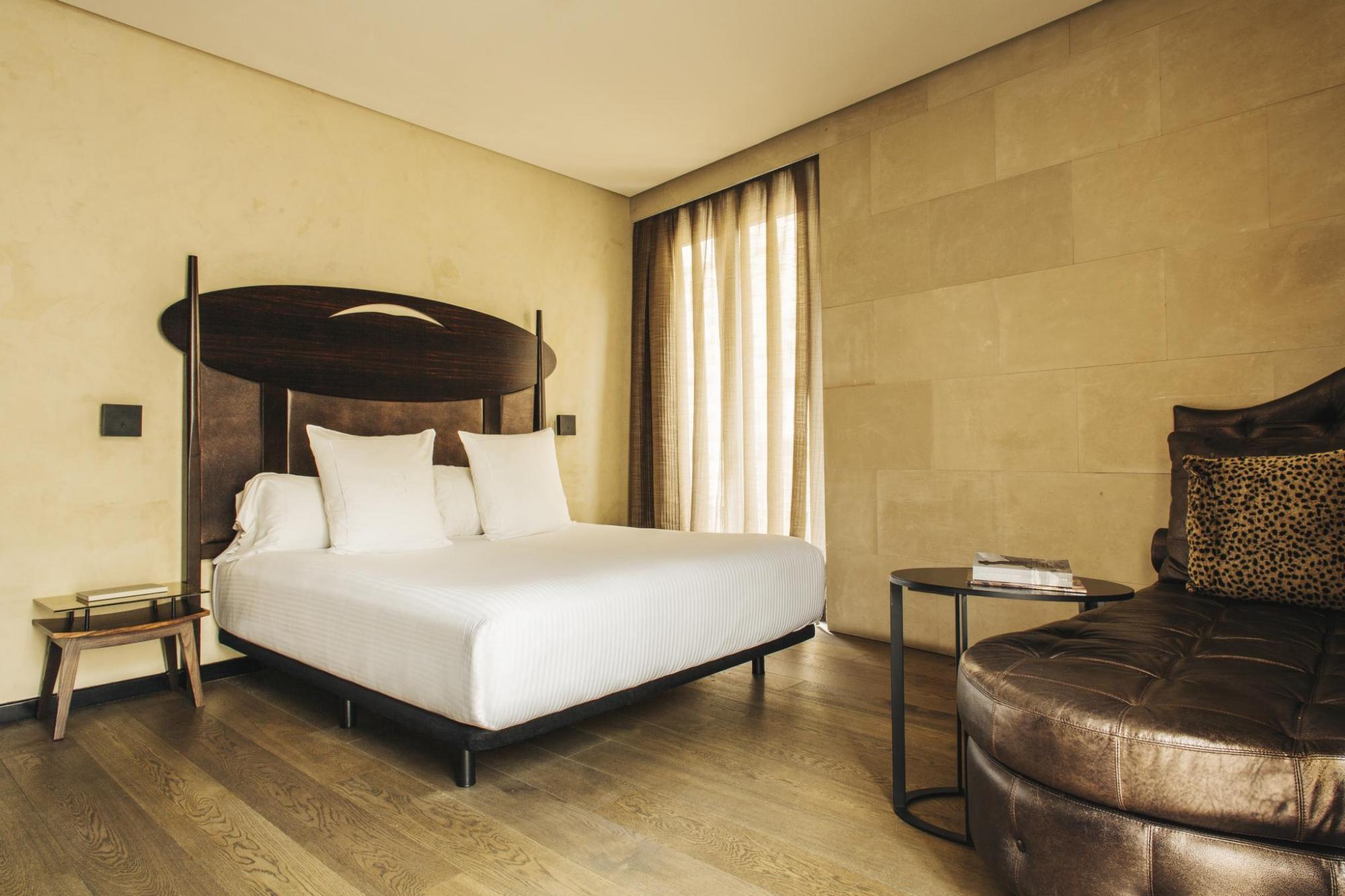 Hotel Bagues Deluxe Room with ample space, gold chaise longue, and arty wooden headboard