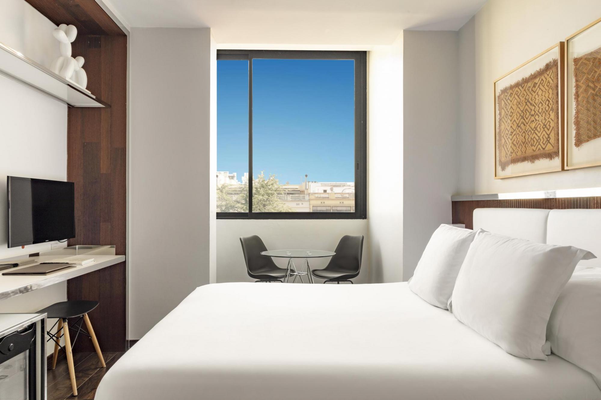 Hotel Balmes Executive Room with window looking out onto blue sky, and double bed with white linens