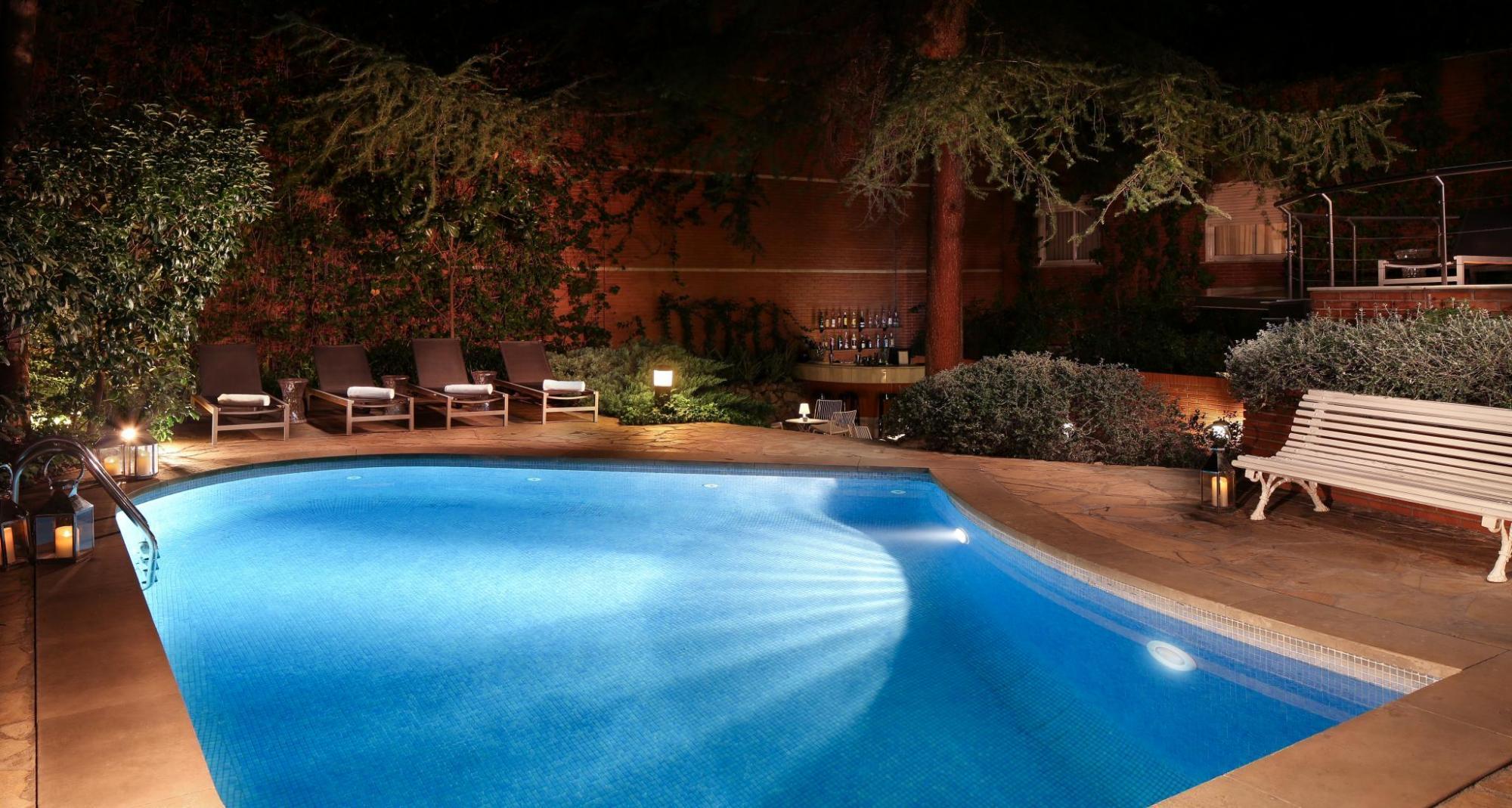 Hotel Balmes pool in the evening, with underwater lights, and loungers under the trees