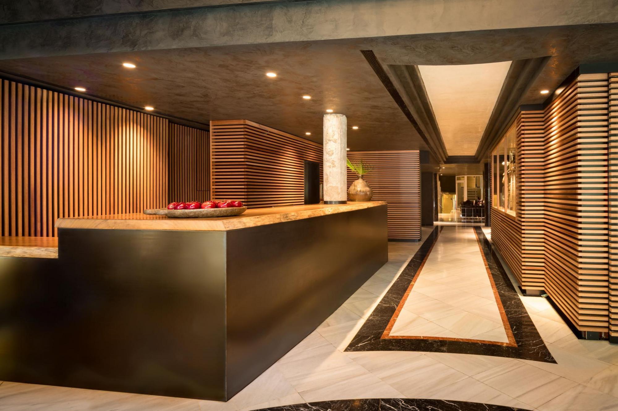 Hotel Balmes reception, with warm wood-panelled walls, a sleek simple desk, and marble floor