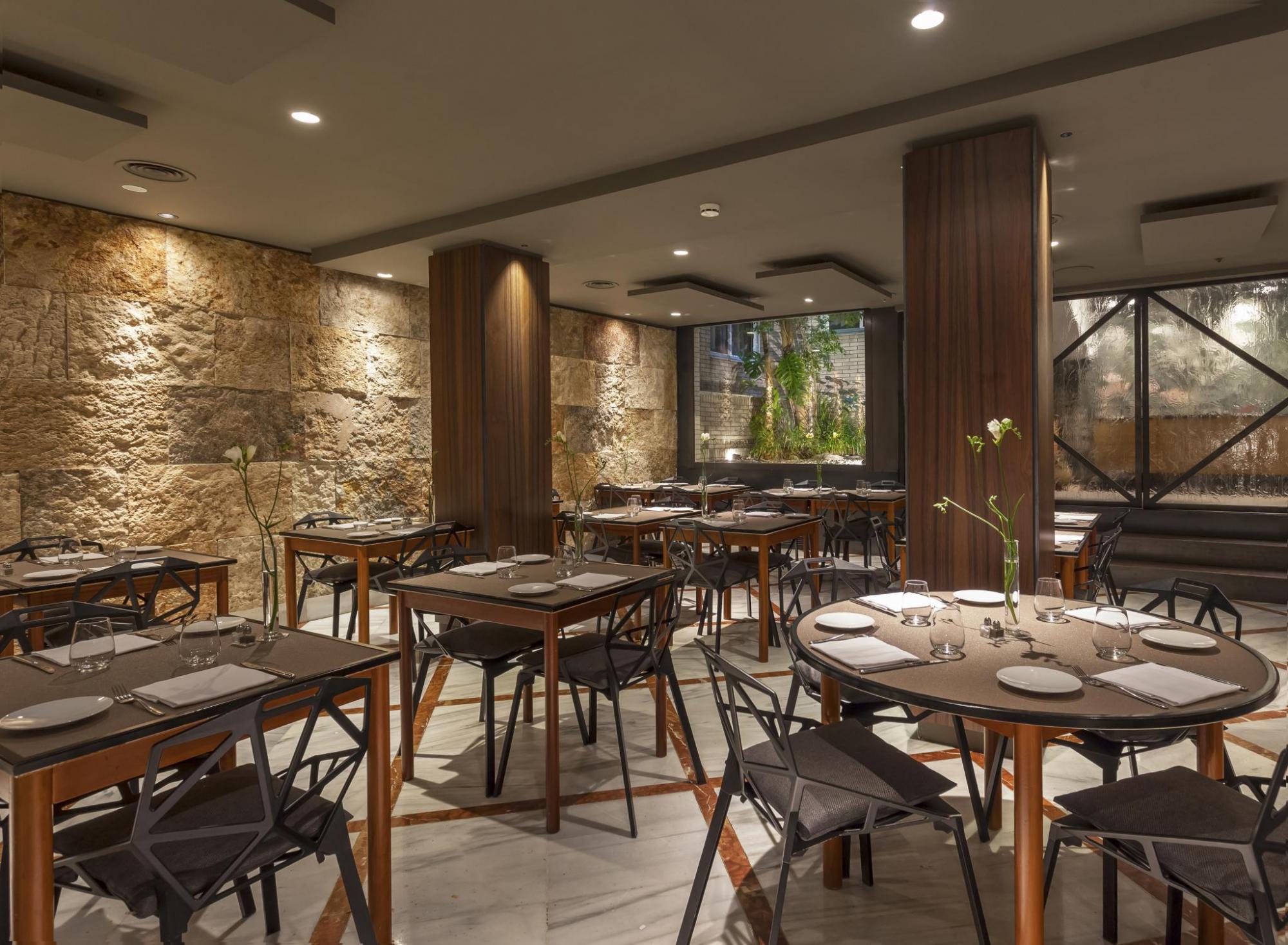 Hotel Balmes restaurant with exposed rough stone walls, contrasted with modern, sleek neutral-coloured furnishings and large windows