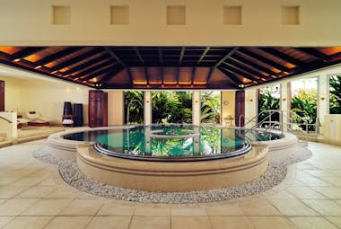 Indoor pool spa area with wood pannelled ceiling and circular pool