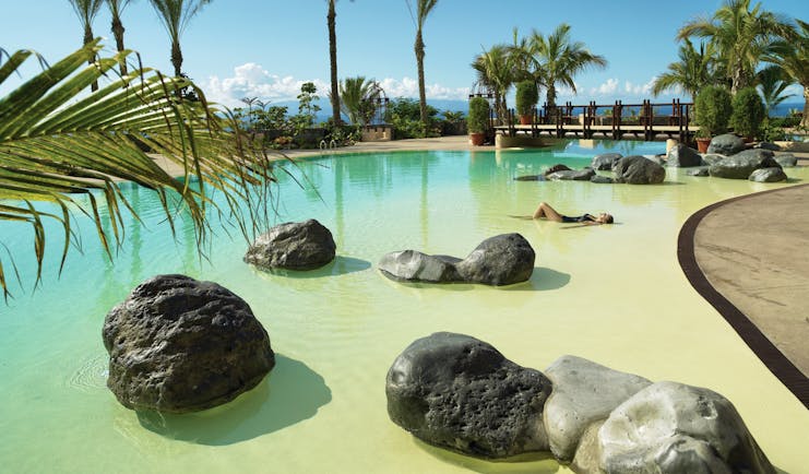 Abama Tenerife pool terrace palm trees rocks in water