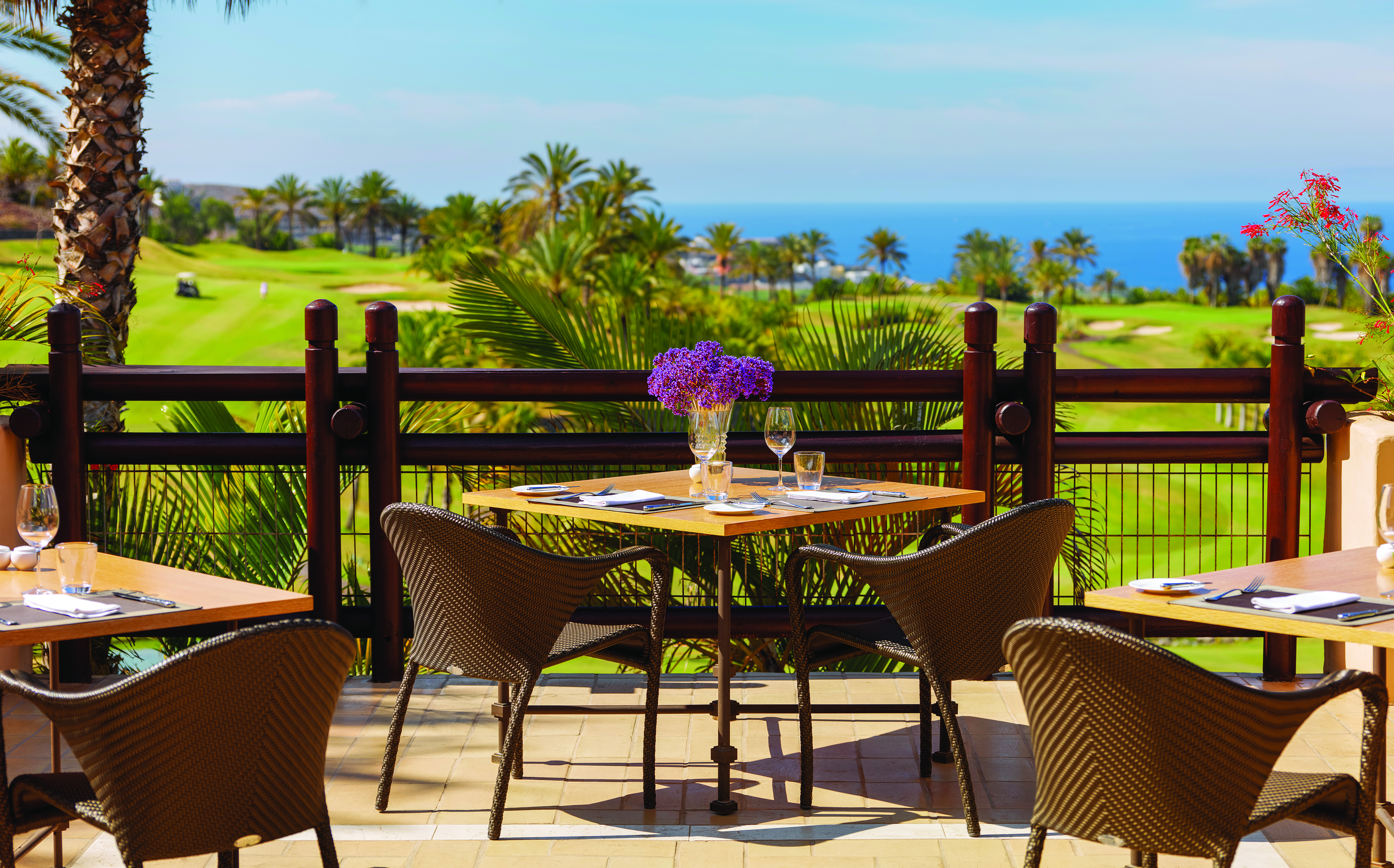 Outdoor dining terrace with tables and chairs set out for dining on wooden decking 