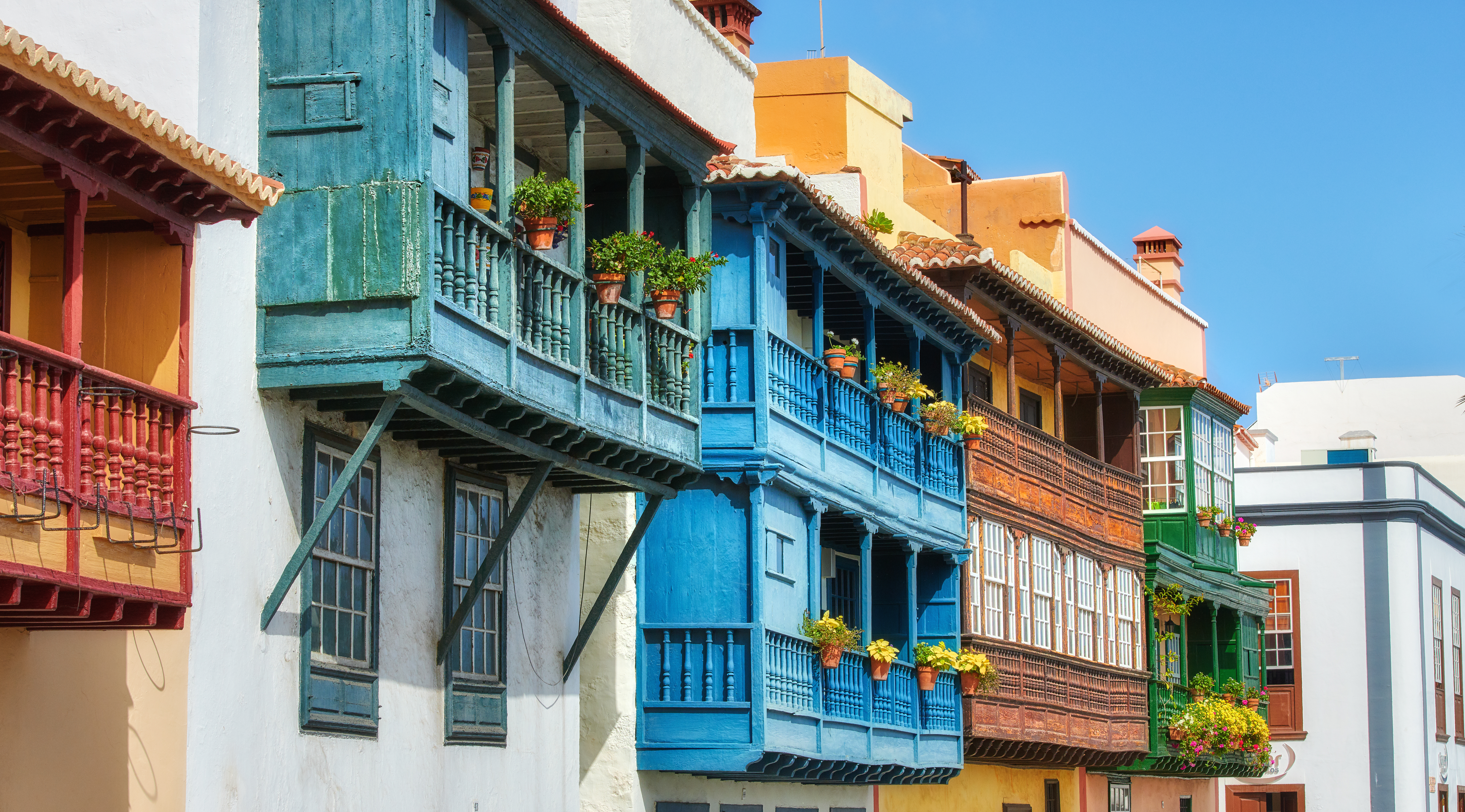Galleried houses with balconies of pot plants all painted different colours in Santa Cruz de la Palma