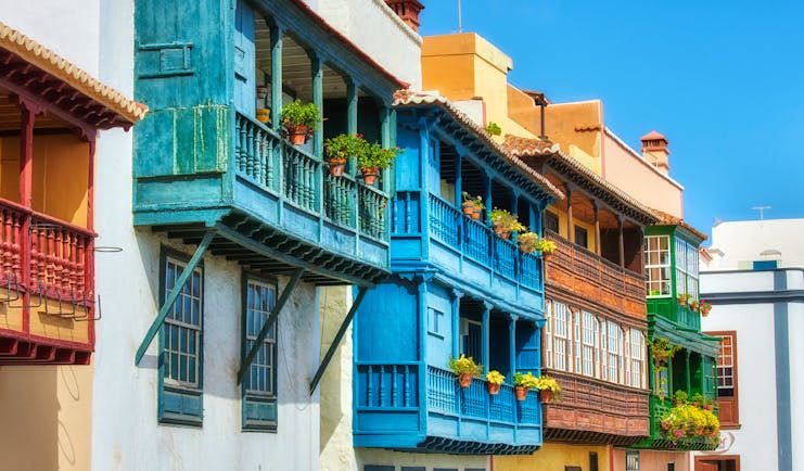 Galleried houses with balconies of pot plants all painted different colours in Santa Cruz de la Palma