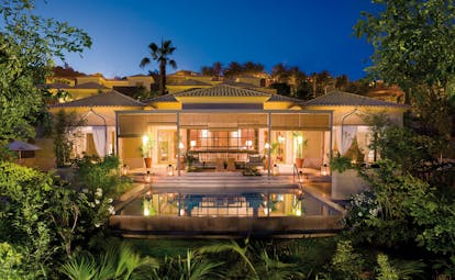 Exterior of  hotel lit up at night with greenery surrounding