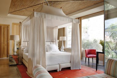 Villa bedroom with large white four poster bed  and sofa
