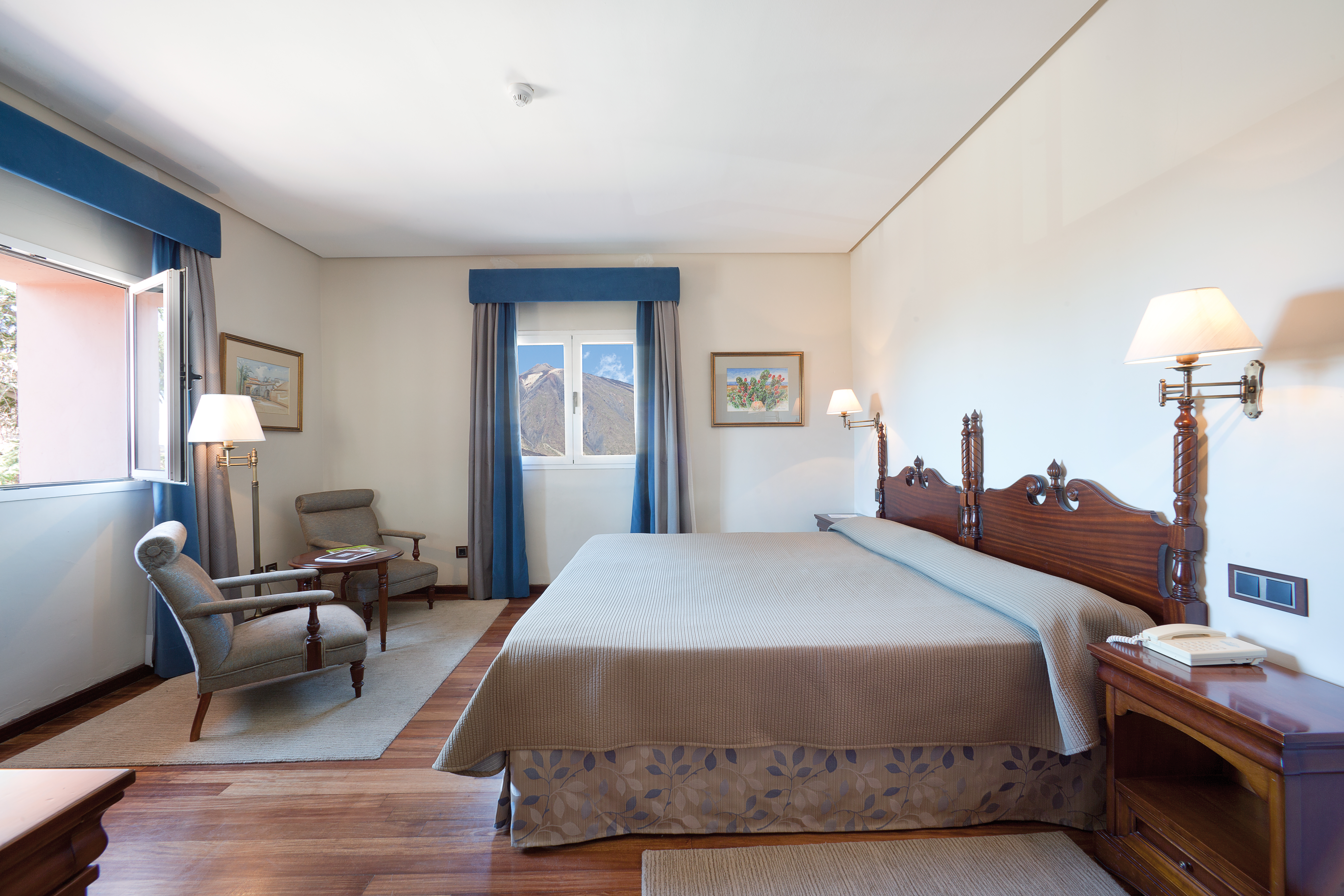 Bedroom with large double bed, arm chair and windows