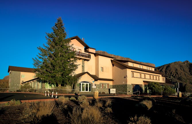 Hotel entrance with big fur tree outisde and stone building