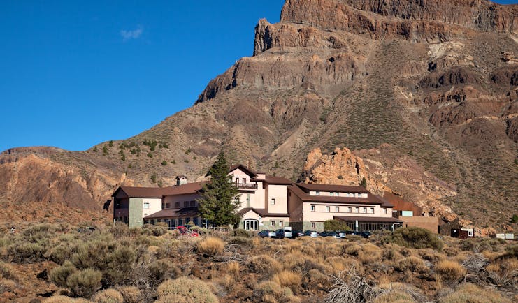 Exterior of hotel shown in front of huge mountain