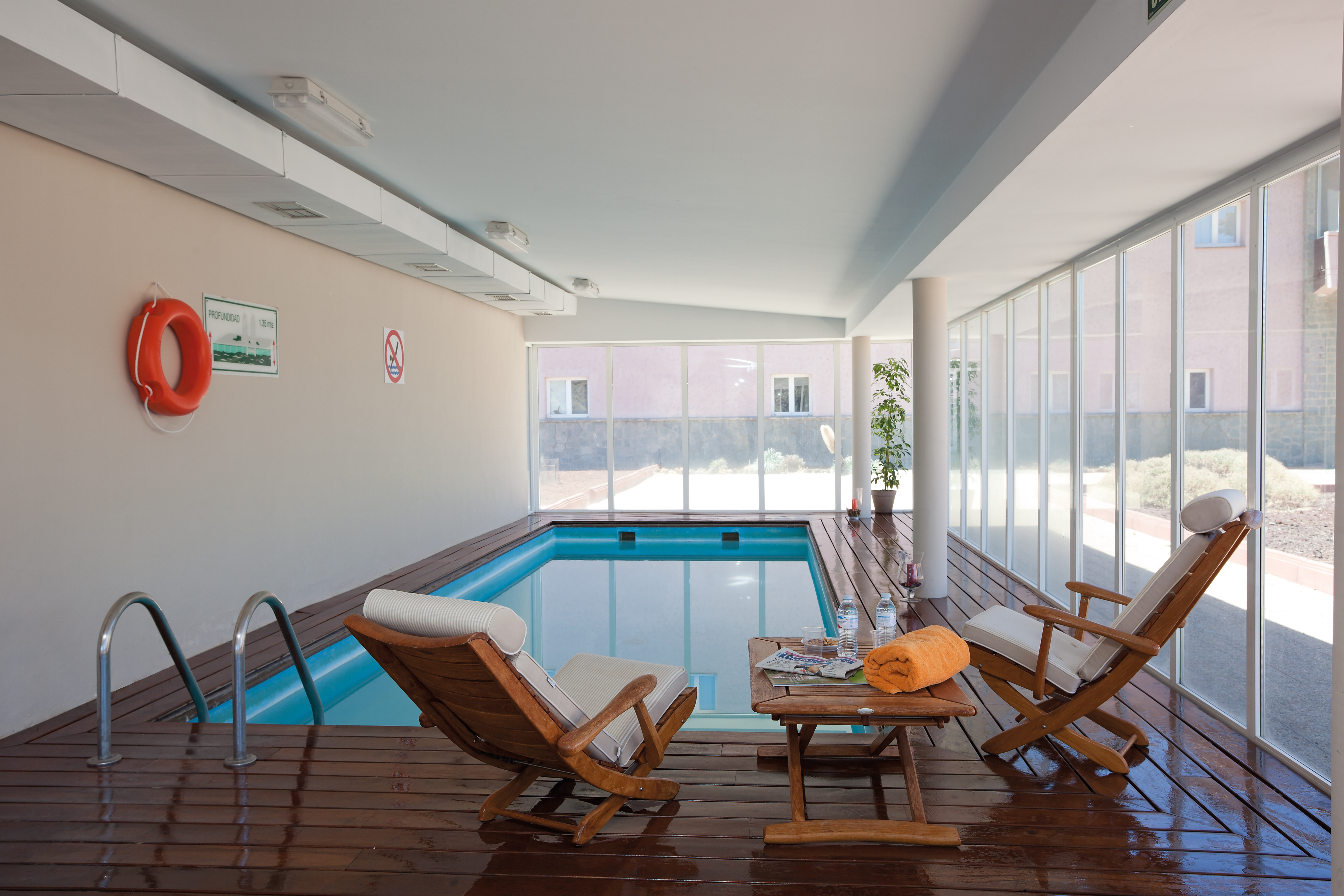 Indoor swimming pool with deck chairs set up around the edges