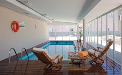 Indoor swimming pool with deck chairs set up around the edges