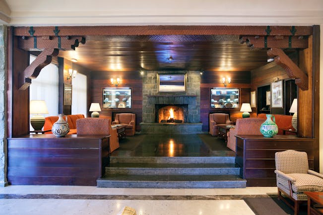 Lobby area with fire place, sofas and arm chairs and wood pannelled ceilings