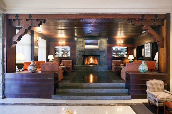 Lobby area with fire place, sofas and arm chairs and wood pannelled ceilings