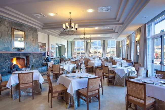 Restaurant with tables and chairs set up in a room with a fireplace and views over the mountains