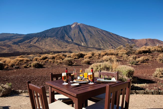 Terrace dining area with table set out outside with drinks on looking over the mountains