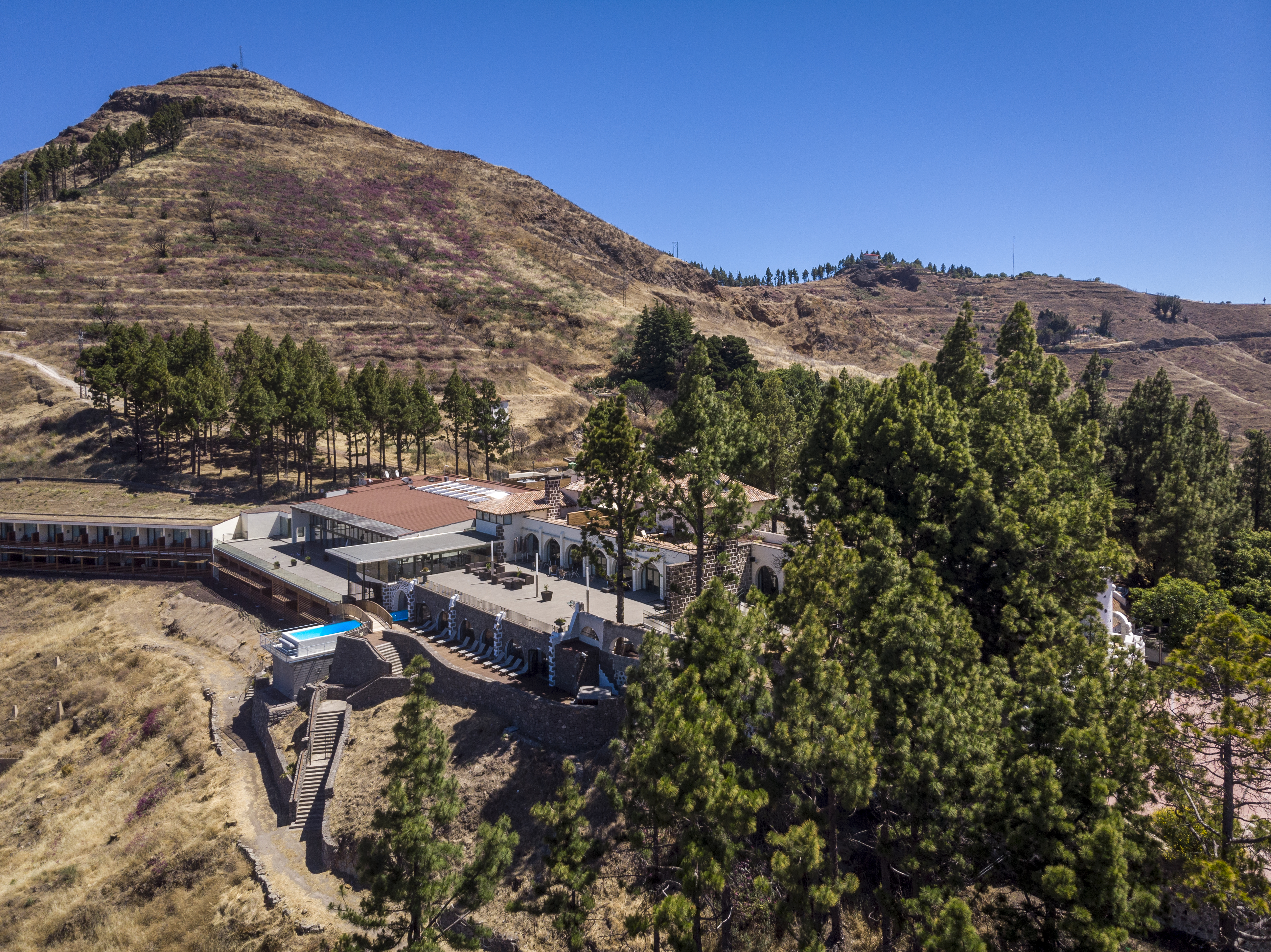 Aerial view of hotel, shown amongst trees and mountains 