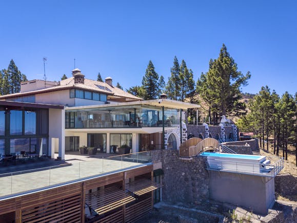 Exterior of hotel with outdoor swimming pool, terrace area and dining area with view of mountains 