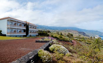 Exterior of hotel with white building and looking out over the gardens and sea