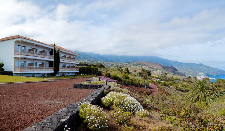 Exterior of hotel with white building and looking out over the gardens and sea