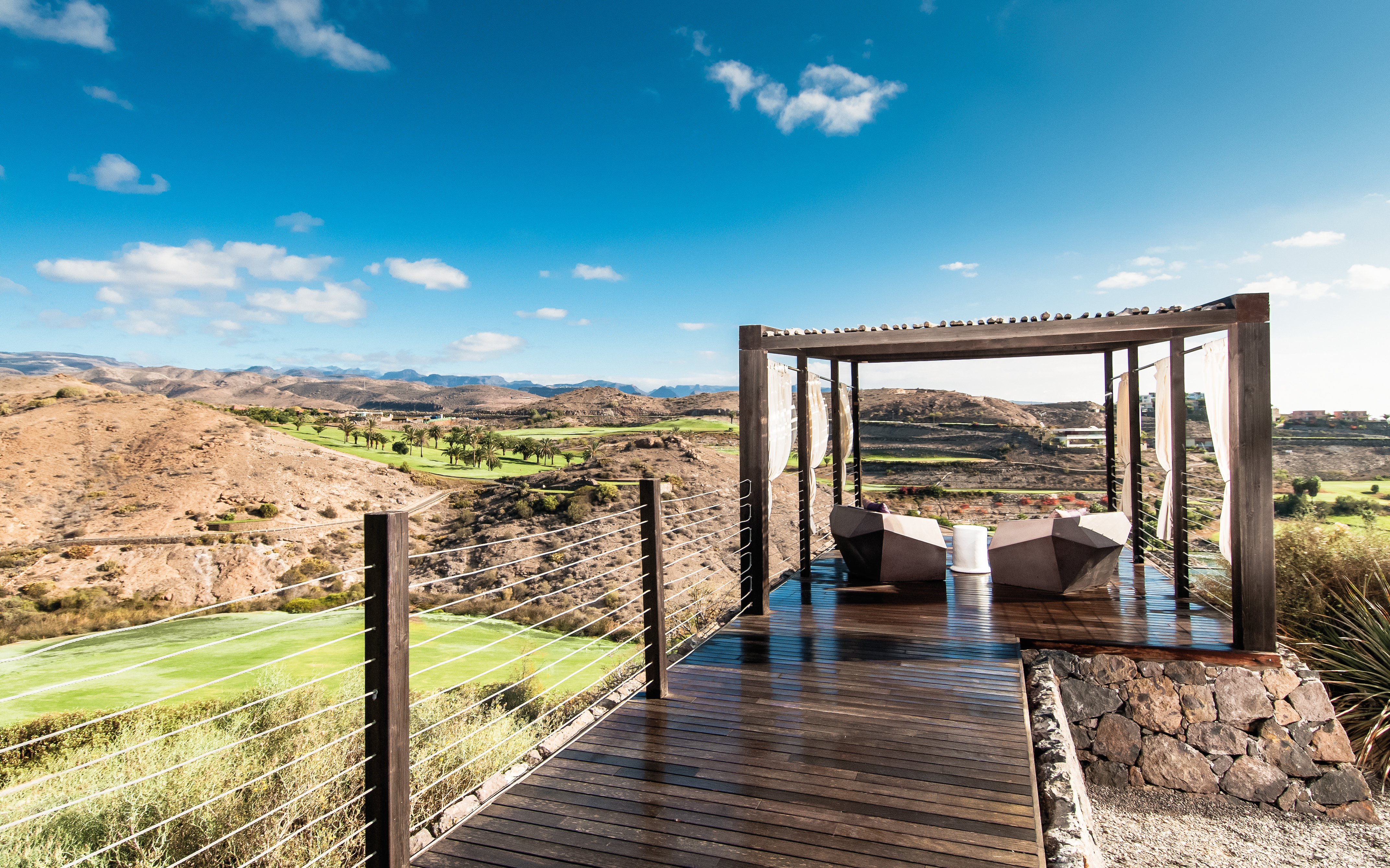 Golf viewing area with wood pannelled bridge, seating area covered by a porch and view of the golf course