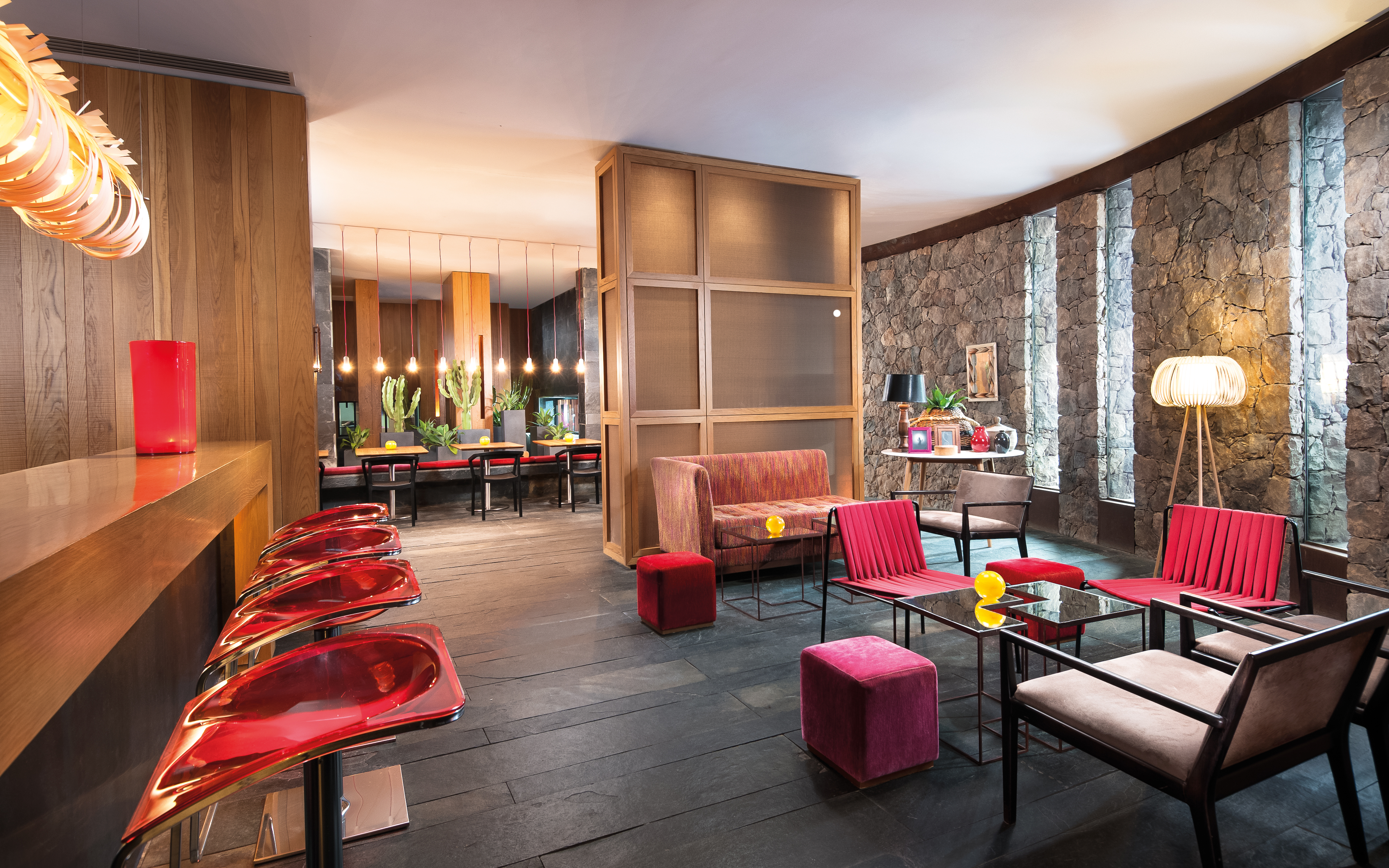 Restaurant with red colour scheme, stone walls and a wooden bar area