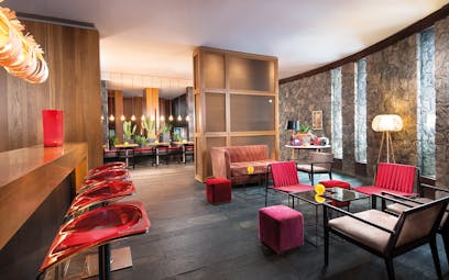 Restaurant with red colour scheme, stone walls and a wooden bar area